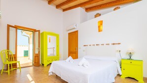 A bedroom with a bed, a yellow chair, a green dresser, and a wooden ceiling. - ES MUSSOL - Villa with private pool in SA POBLA. Free WiFi (Sa Pobla)