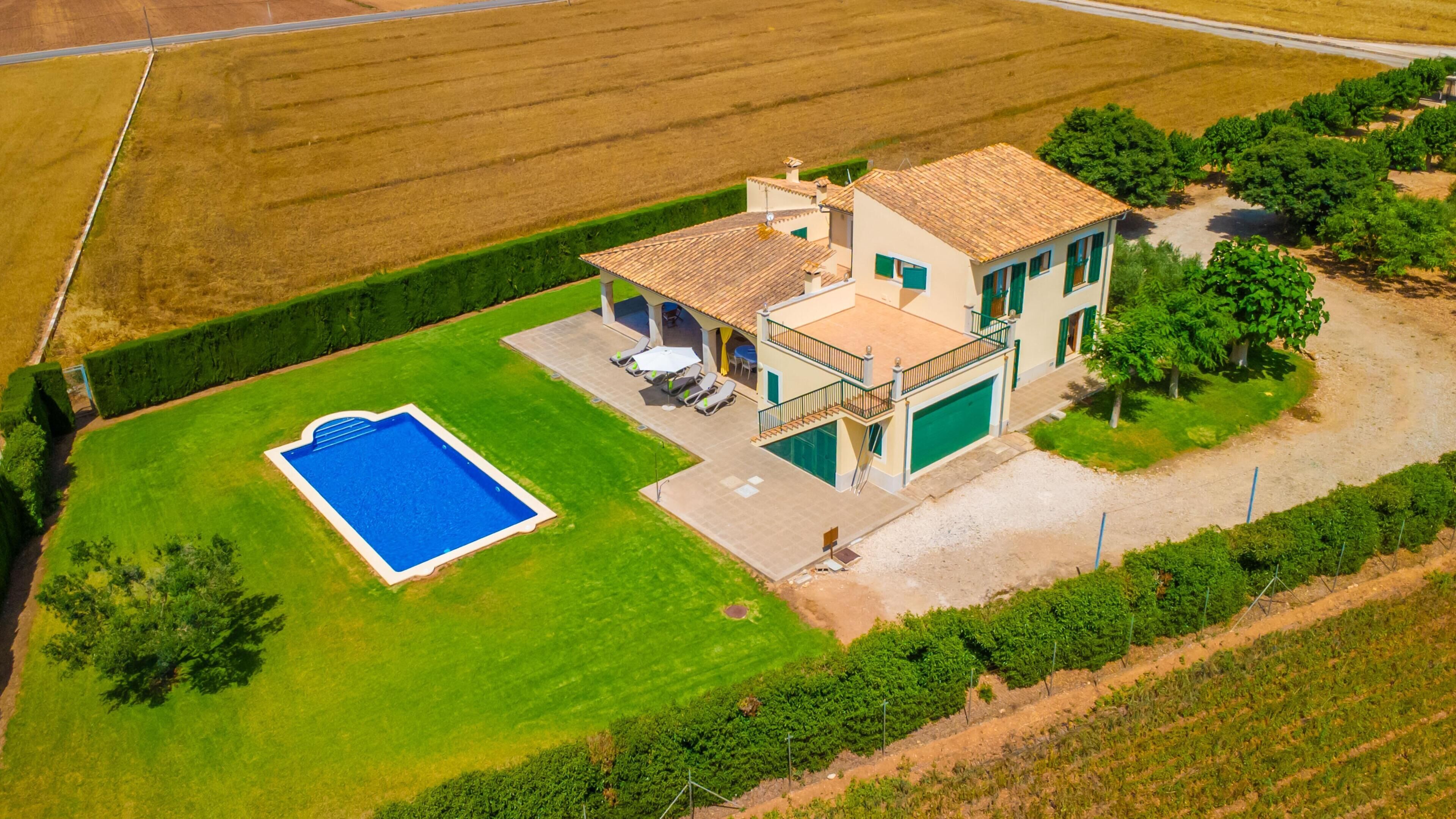 A two-story house with a swimming pool, a covered patio, and a fenced yard.