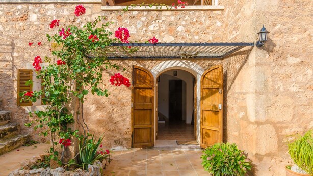 Un edificio in pietra con porte in legno e un ingresso piastrellato.