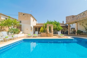 A swimming pool with lounge chairs and a stone structure in the center.