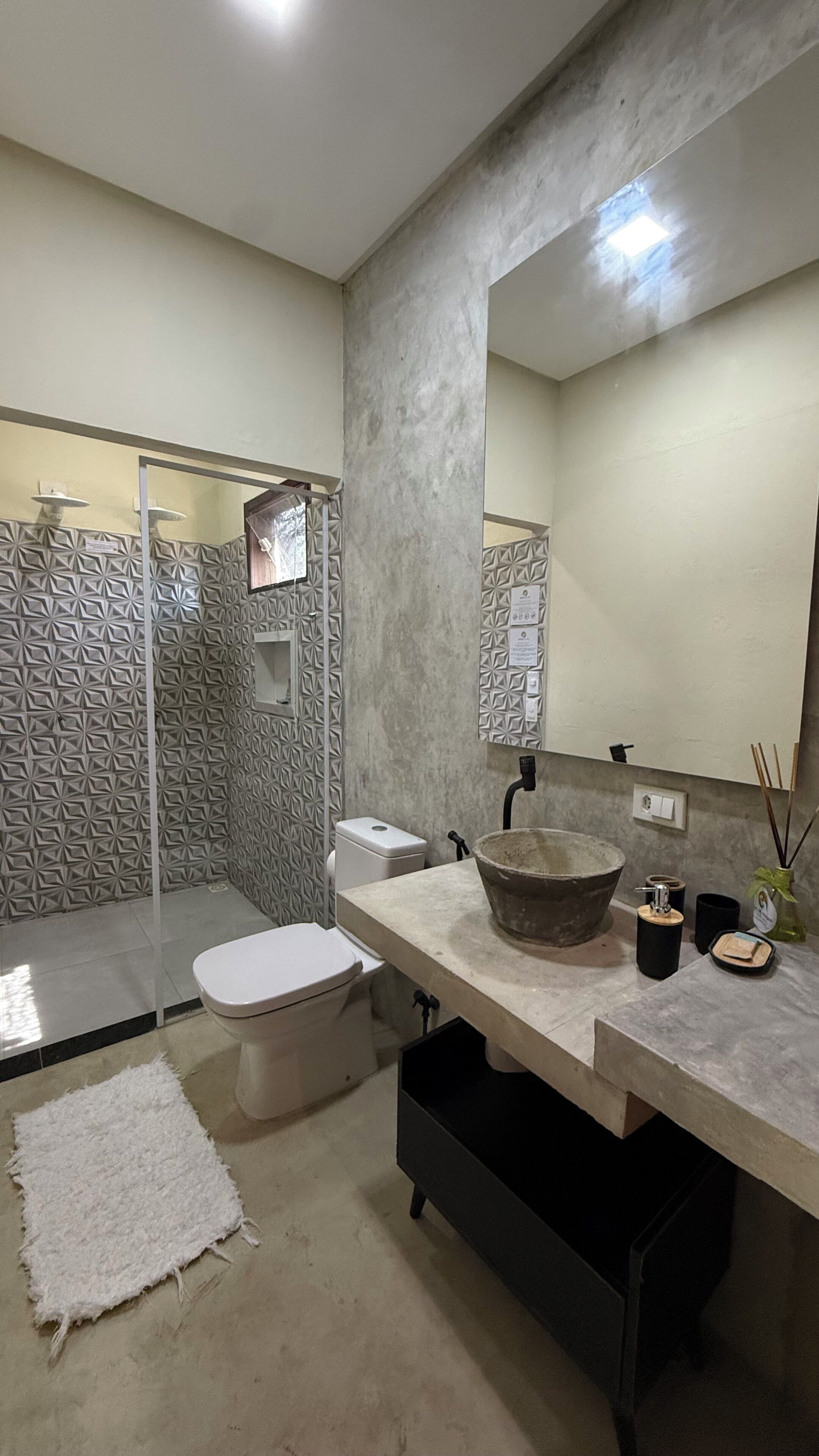 Ein Badezimmer im modernen Design mit einem großen Spiegel, einem Haubenwaschbecken und einer Toilette.
