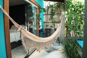 Un hamac dans une pièce dotée d’une porte vitrée, d’une petite table et d’une plante en pot.