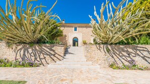 A stone pathway leading to a building with a tiled roof and an arched entrance. - SON SIMÓ VELL - Villa with private pool in Alcúdia. (Alcúdia)