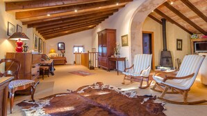 Un vaste salon doté de poutres apparentes, d’une cheminée et d’un tapis en peau de vache.