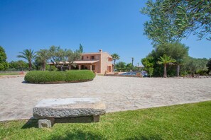 A spacious courtyard with a stone pathway, a small stone bench, and a building with a tiled roof. - SON AUBA - Villa with private pool in Muro. Free WiFi (Muro)