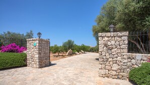 Un sendero de piedra que conduce a una entrada con puerta, un farol y un cartel.