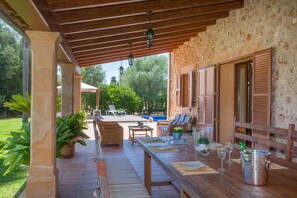 A covered outdoor patio with wooden furniture, a pool, and a stone wall. - SON AUBA - Villa with private pool in Muro. Free WiFi (Muro)