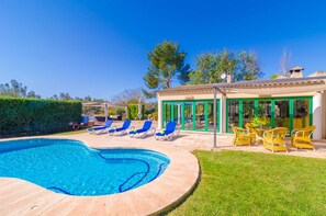 A swimming pool with lounge chairs, a covered patio area, and a building with green-framed windows. - CAN RITO - Villa with private pool in FELANITX. Free WiFi (Felanitx)