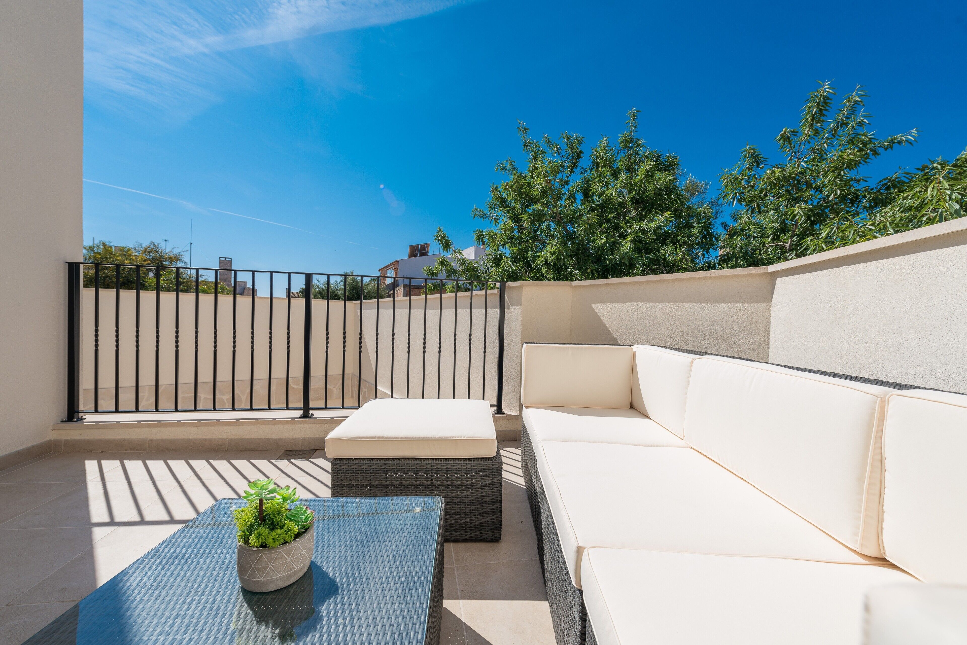 Een balkon met een bank, een bijzettafeltje en een bloempot.