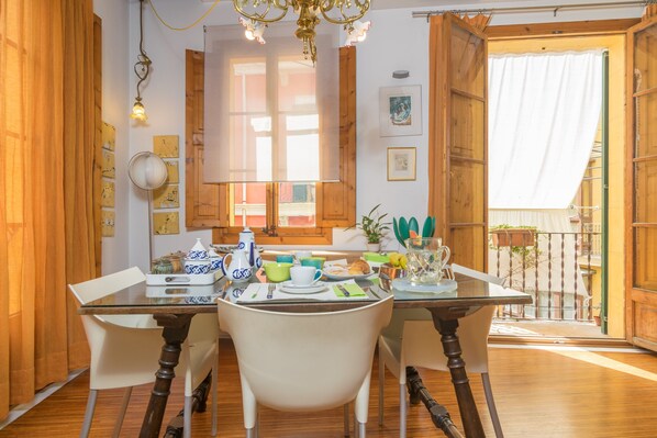 A dining area with a glass table, white chairs, wooden cabinets, and a view of the outside.
