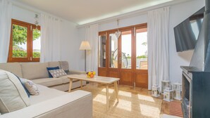 A living room with a sofa, a coffee table, a TV, and a fireplace. - MURTA 26 - Villa with private pool in SA COMA. Free WiFi (Sant Llorenç des Cardassar)