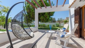 A patio with a hanging chair, a rocking chair, and a small table with a vase. - MURTA 26 - Villa with private pool in SA COMA. Free WiFi (Sant Llorenç des Cardassar)