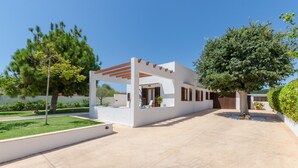 A modern outdoor patio area with a pergola, a white building, and a large tree. - MURTA 26 - Villa with private pool in SA COMA. Free WiFi (Sant Llorenç des Cardassar)