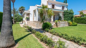 Une maison à deux étages, avec des fondations en pierre, un balcon et une pelouse bien entretenue.