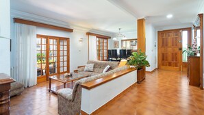 Un salon spacieux, doté d’un canapé, d’une table basse et offrant une vue sur le jardin grâce à de grandes fenêtres.