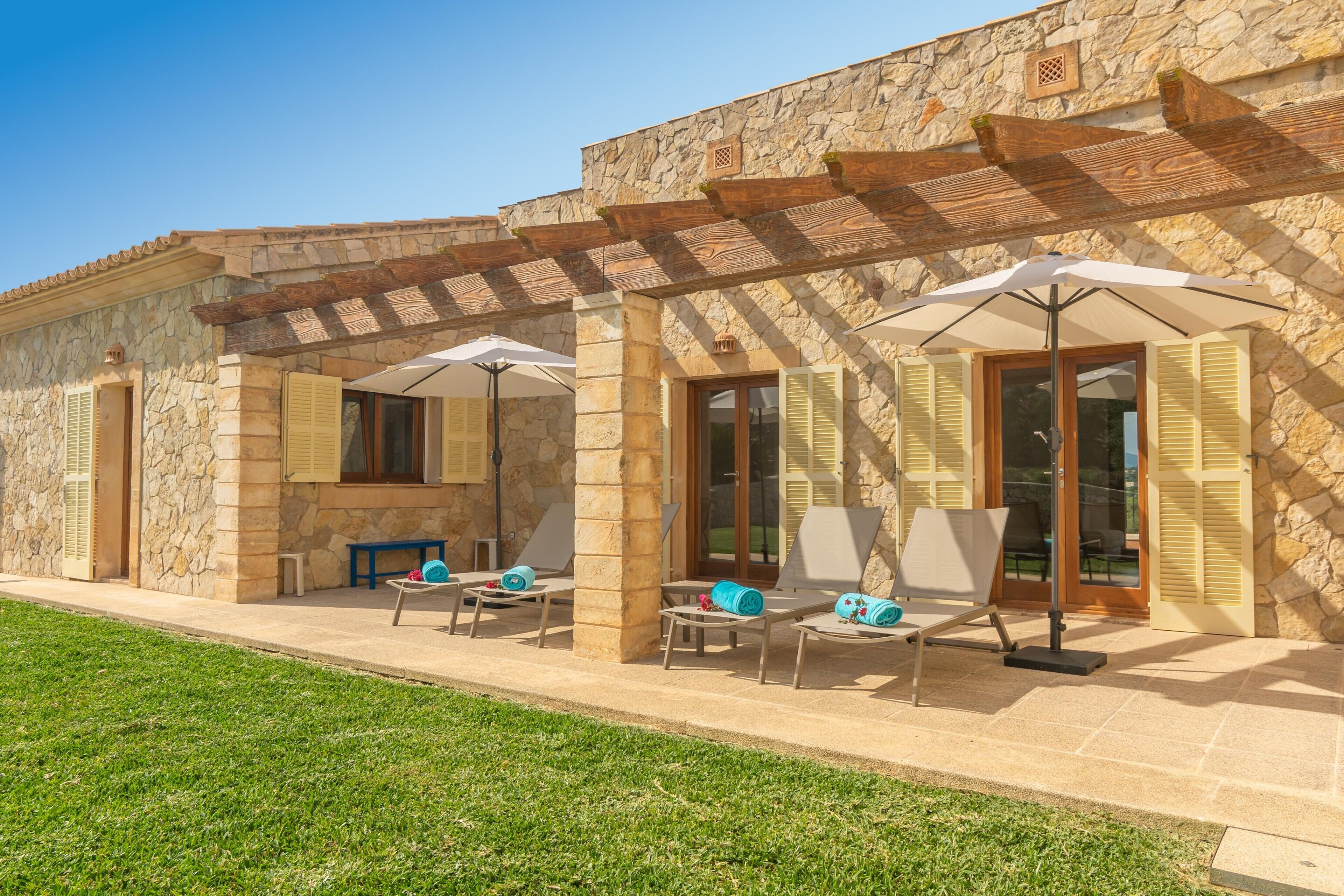 A stone building with a covered patio area featuring outdoor seating and umbrellas.
