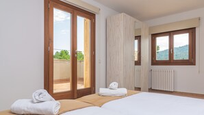 A hotel room with two beds, a sliding glass door to the balcony, a large window, and a radiator. - FETGET-CAN BOSCO - Nice country house with private pool close to the beach. Free WiFi (Son Servera)