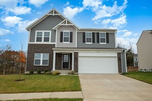 A two-story residential house with a garage, a front porch, and a well-maintained lawn.