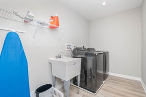 A compact laundry room with a washing machine, dryer, and a sink.