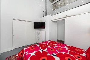 Un dormitorio con cama, armario, cómoda y televisor.