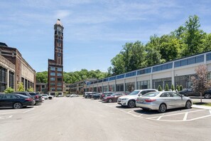 A parking lot with cars, a clock tower, and modern buildings. - 5102 Peters · Large loft near Kings Island. On bike trail/River. (Maineville)