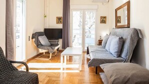 A living room with a sofa, a chair, a coffee table, and a television.