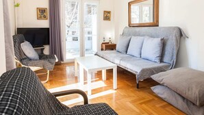 A living room with a sofa, two armchairs, a TV, and a table.