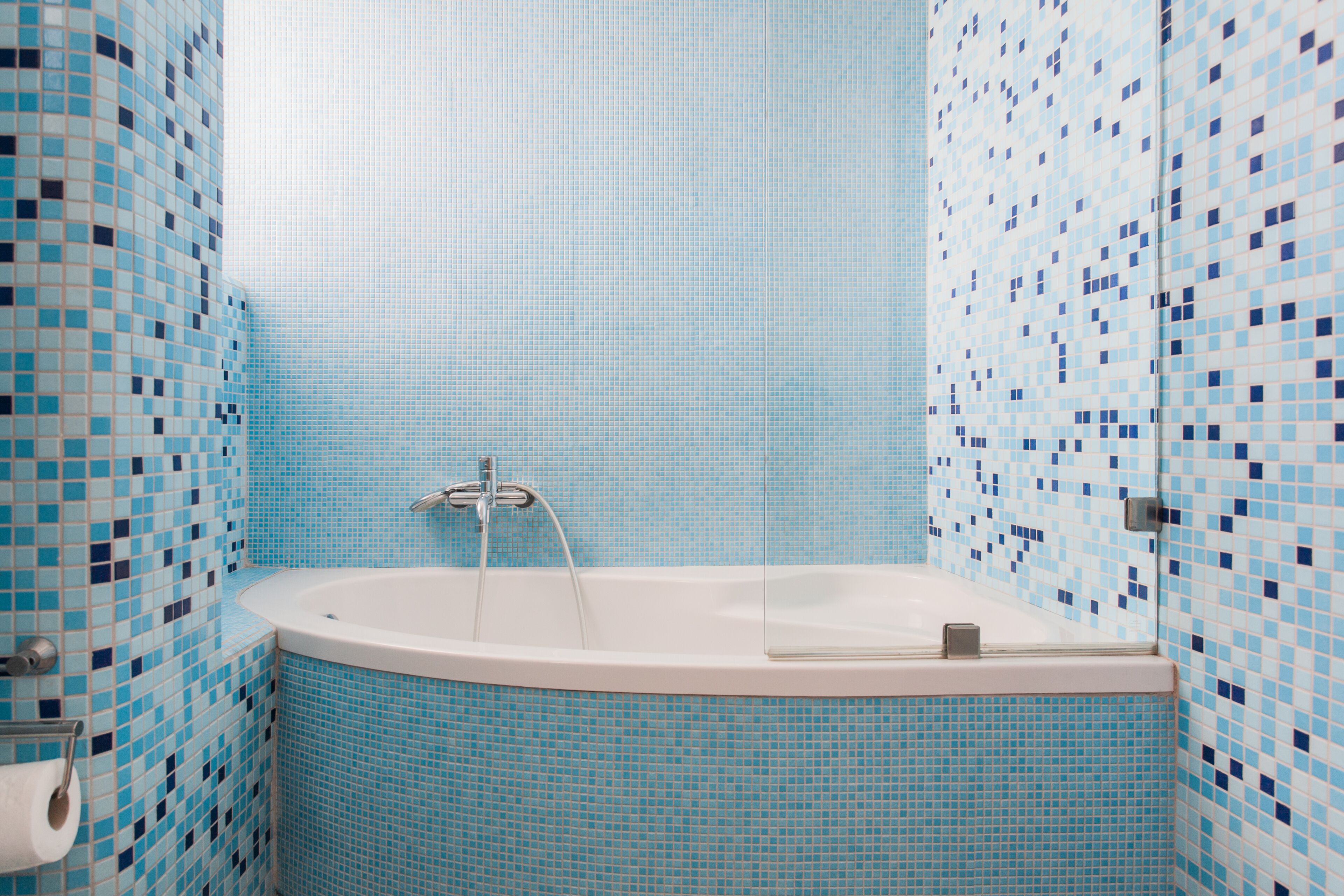Une salle de bain avec une baignoire, des murs carrelés et des toilettes.