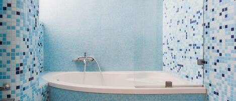 Une salle de bain avec une baignoire, des murs carrelés et des toilettes.