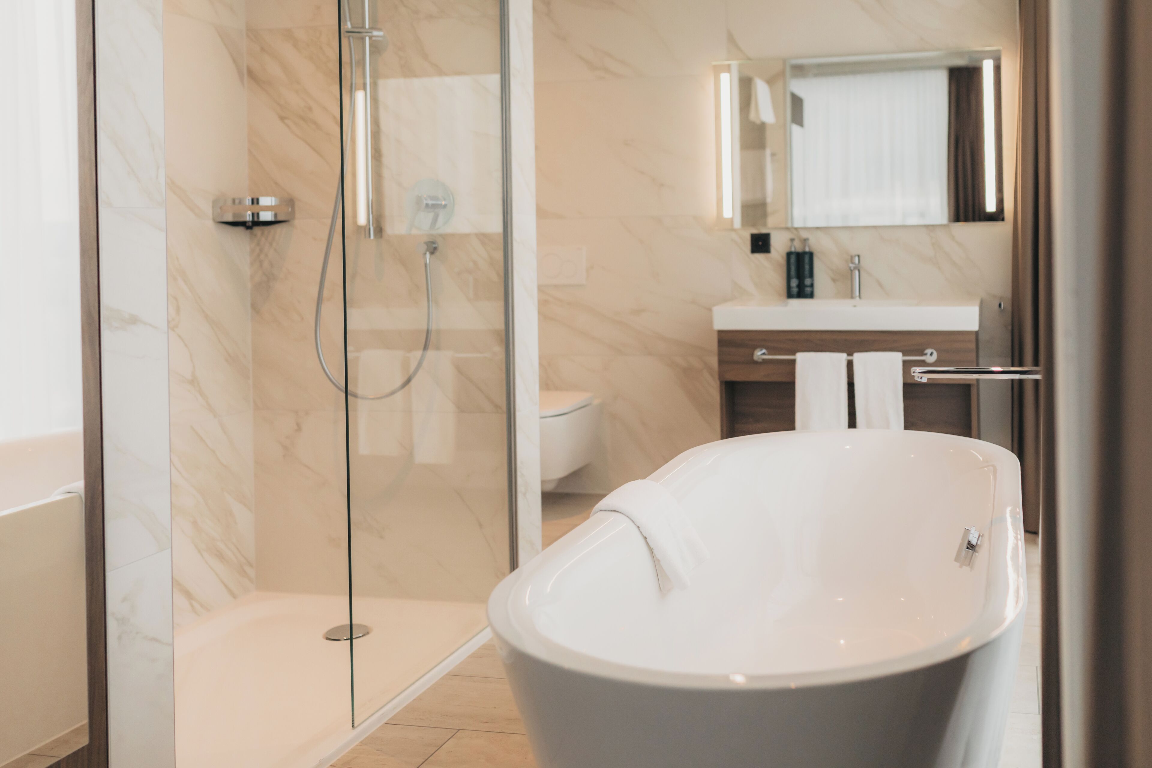 A modern bathroom with a freestanding bathtub, a glass-enclosed shower, and a vanity with a mirror.