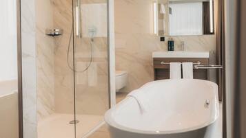 A modern bathroom with a freestanding bathtub, a glass-enclosed shower, and a vanity with a mirror.