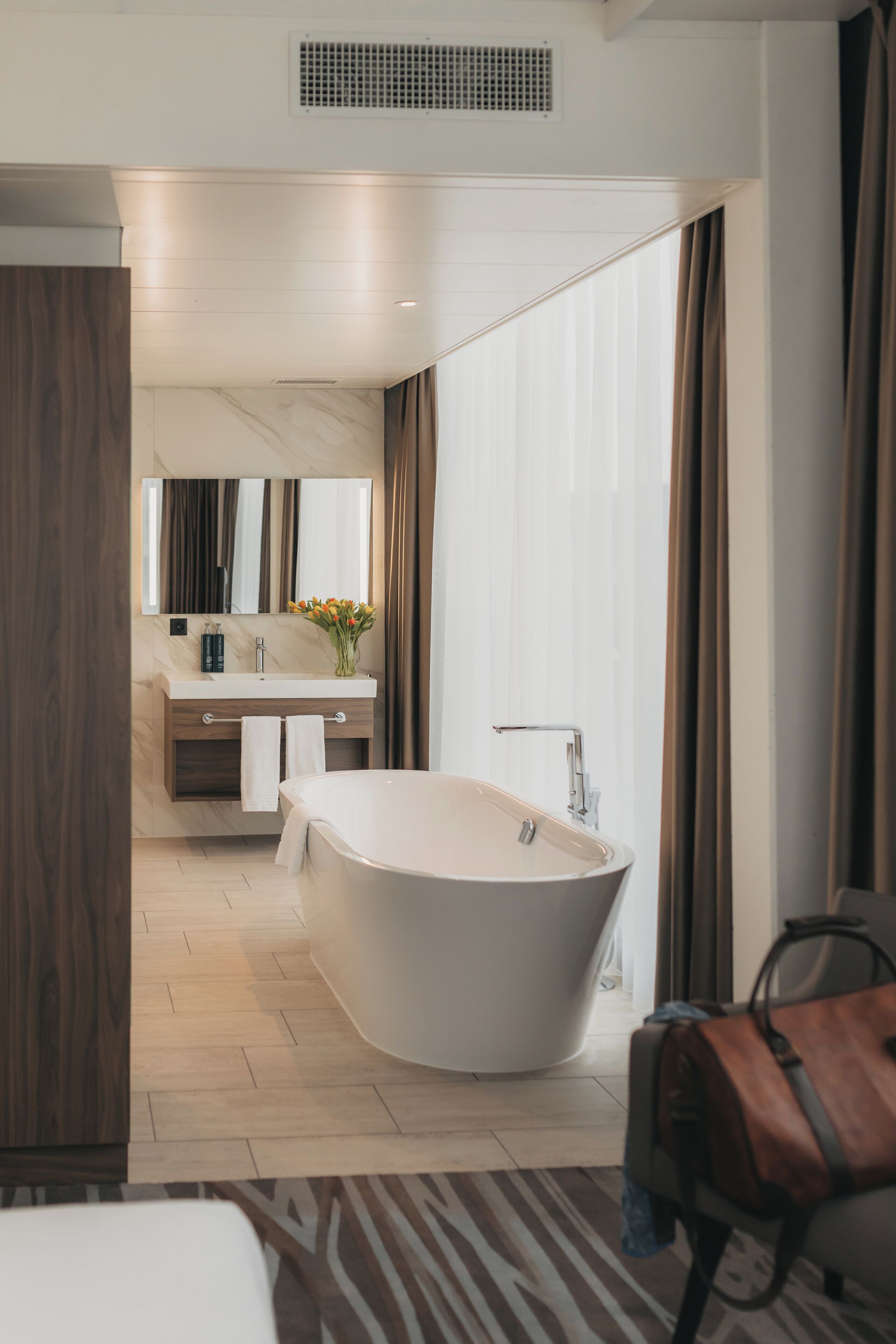 Een moderne badkamer met een vrijstaand bad, een wastafel met spiegel en een douchecabine.