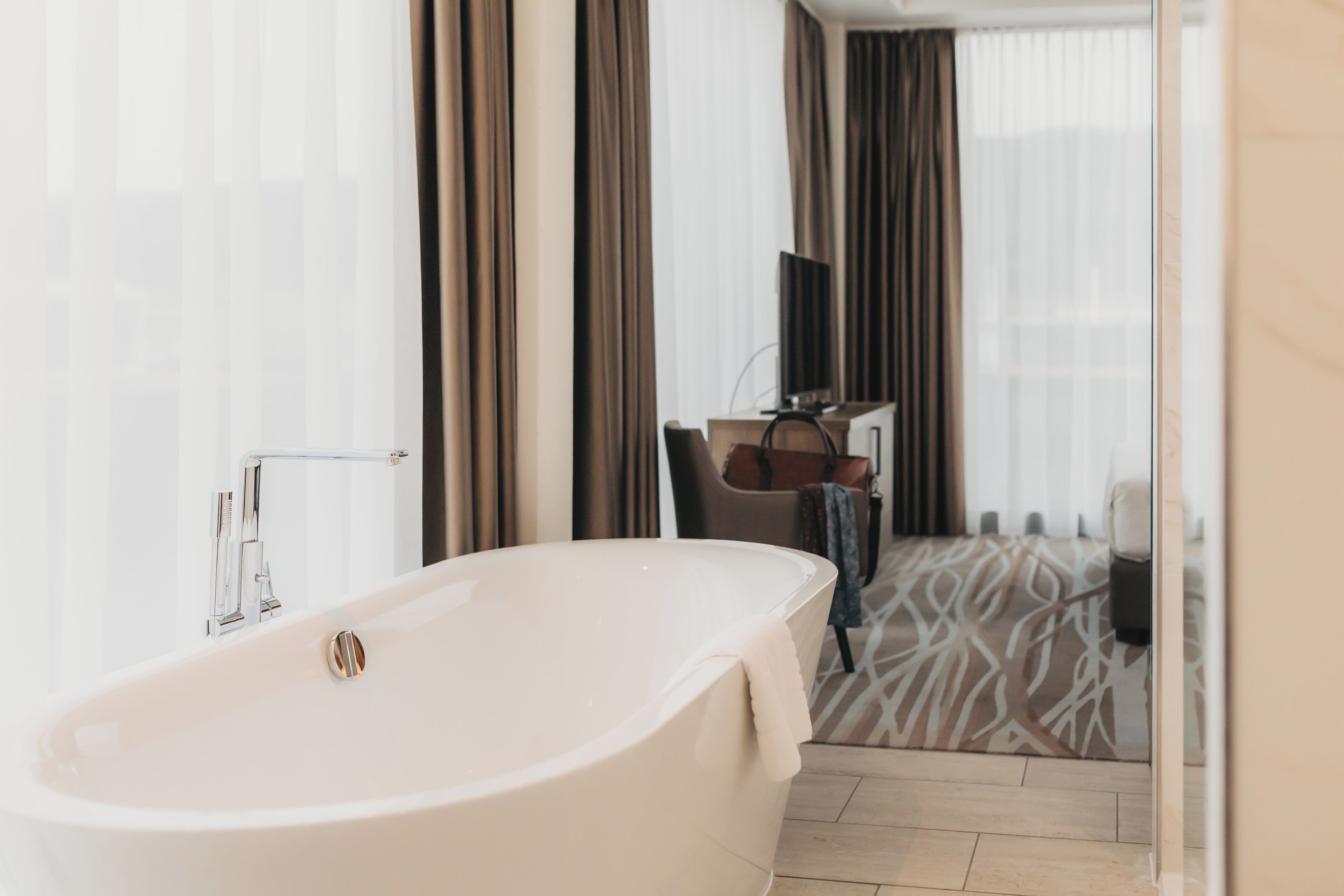 Une salle de bain moderne avec une baignoire sur pieds, un meuble-lavabo avec un miroir et un carrelage décoratif.
