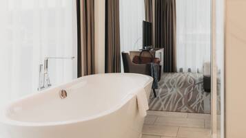 Une salle de bain moderne avec une baignoire sur pieds, un meuble-lavabo avec un miroir et un carrelage décoratif.