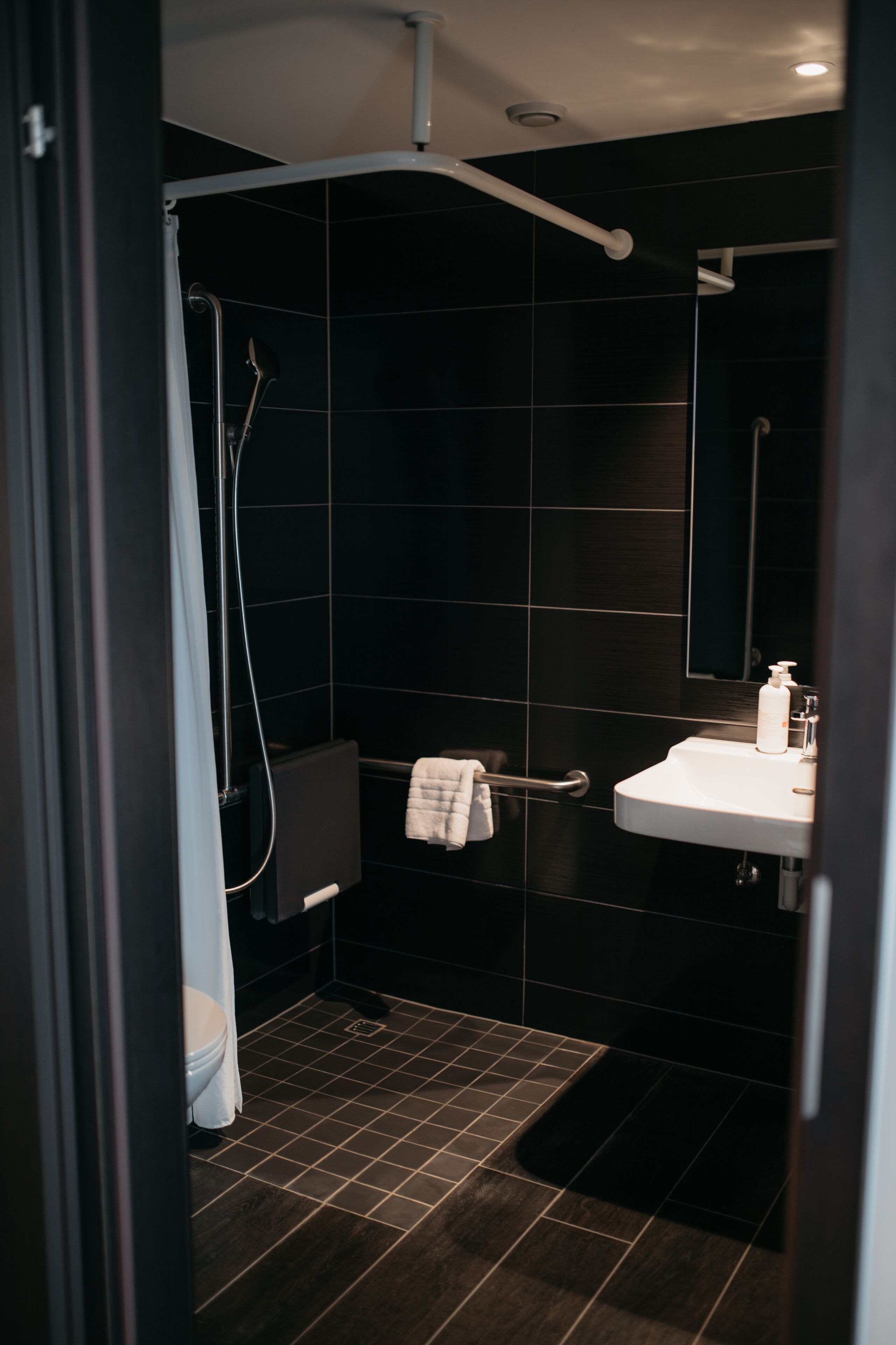 A modern bathroom with a shower, toilet, and sink.