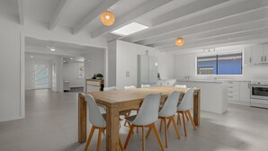 Une cuisine moderne avec des meubles blancs, une table à manger en bois et une grande fenêtre.