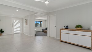 Un espace de vie spacieux et moderne, avec une grande console en bois, une plante en pot et une vue sur l’extérieur par une fenêtre.