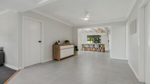 Un hall d’entrée spacieux avec un meuble en bois, un coin repas comprenant une table et des chaises, et un ventilateur de plafond.