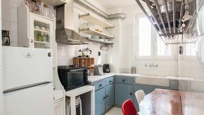 A kitchen with a microwave, stove, and sink. There are cabinets, a table, and chairs. - Fabulous apartment at Exarcheia (Athens)
