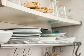 A kitchen shelf with stacked dishes and utensils. - Fabulous apartment at Exarcheia (Athens)