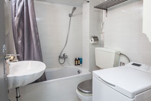 A bathroom with a bathtub, toilet, and washing machine. - Fabulous apartment at Exarcheia (Athens)