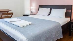 A neatly made bed with a blue and white bedspread, two white pillows, and two folded white towels on the bed. - Fabulous apartment at Exarcheia (Athens)