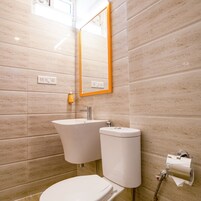 Et badeværelse med toilet, vask og spejl.