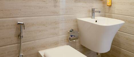 Un baño con un lavamanos blanco, un espejo con marco naranja y una ducha.