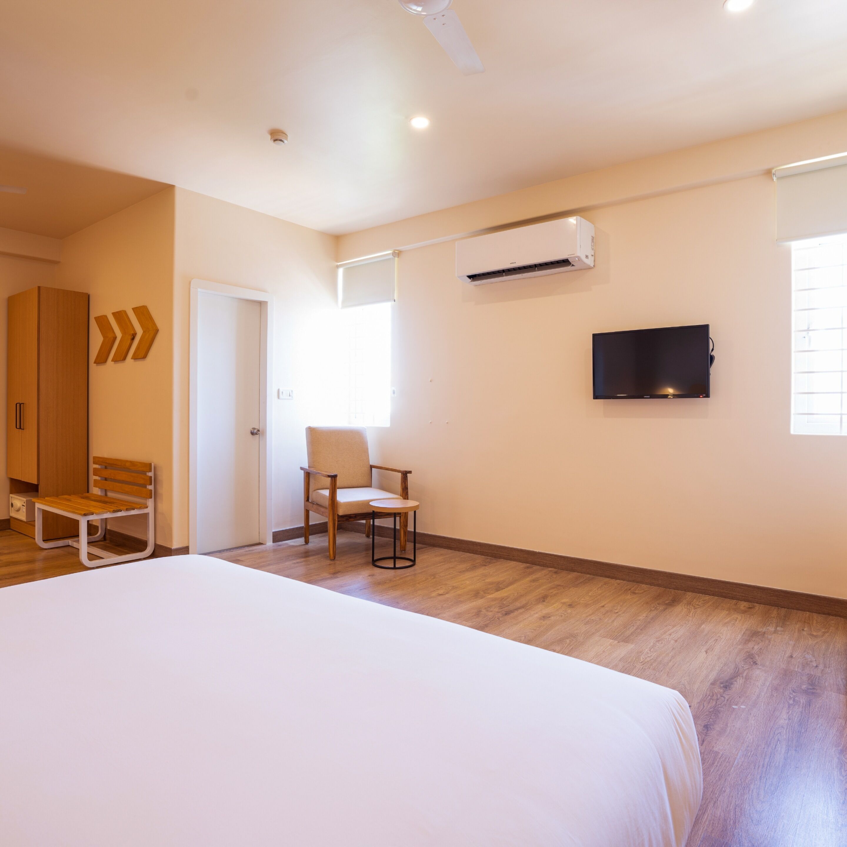 Een hotelkamer met een bed, een stoel, een televisie, een airconditioning en een kledingkast.