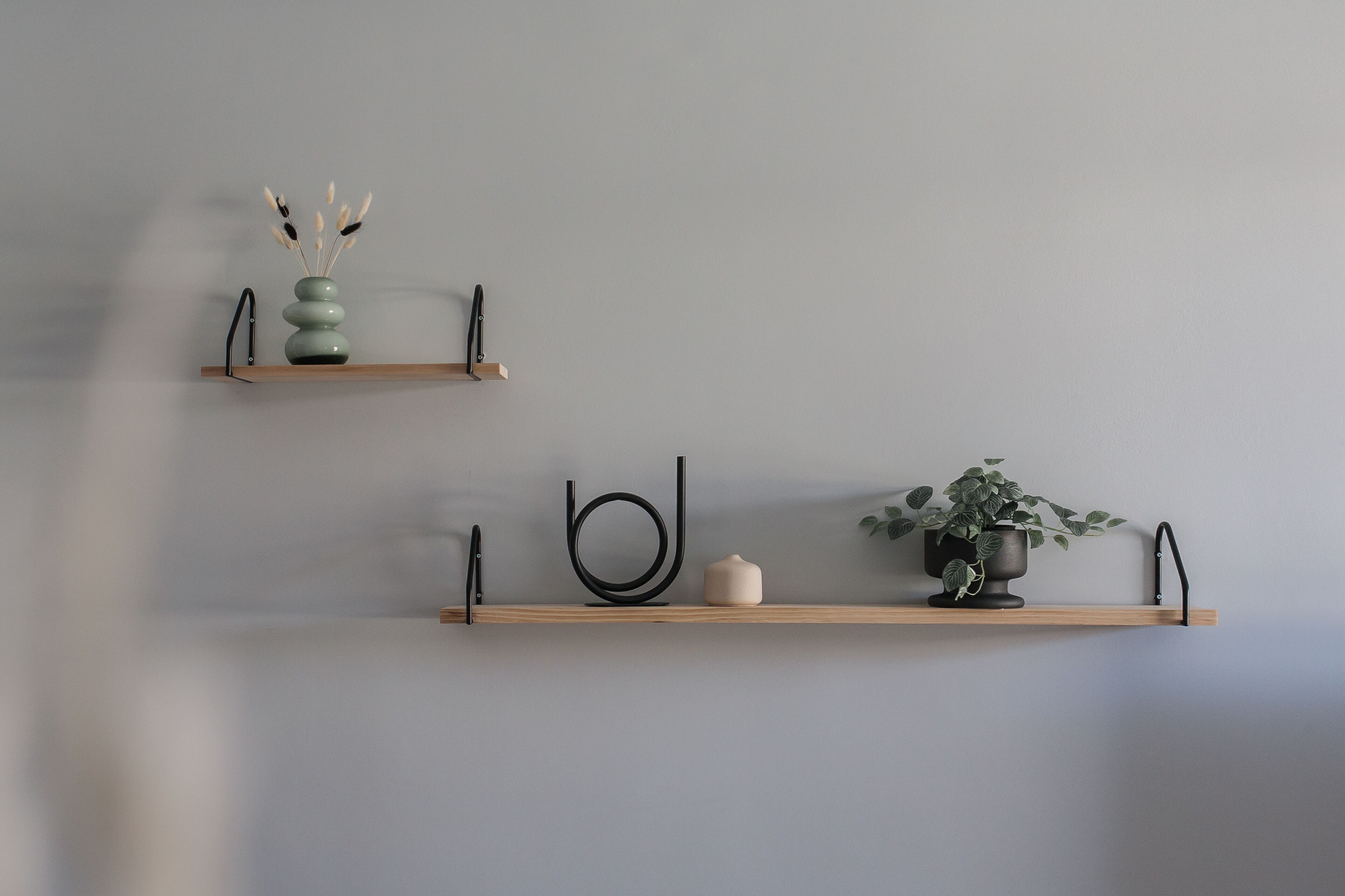Two wooden shelves against a wall, each holding different decorative items.