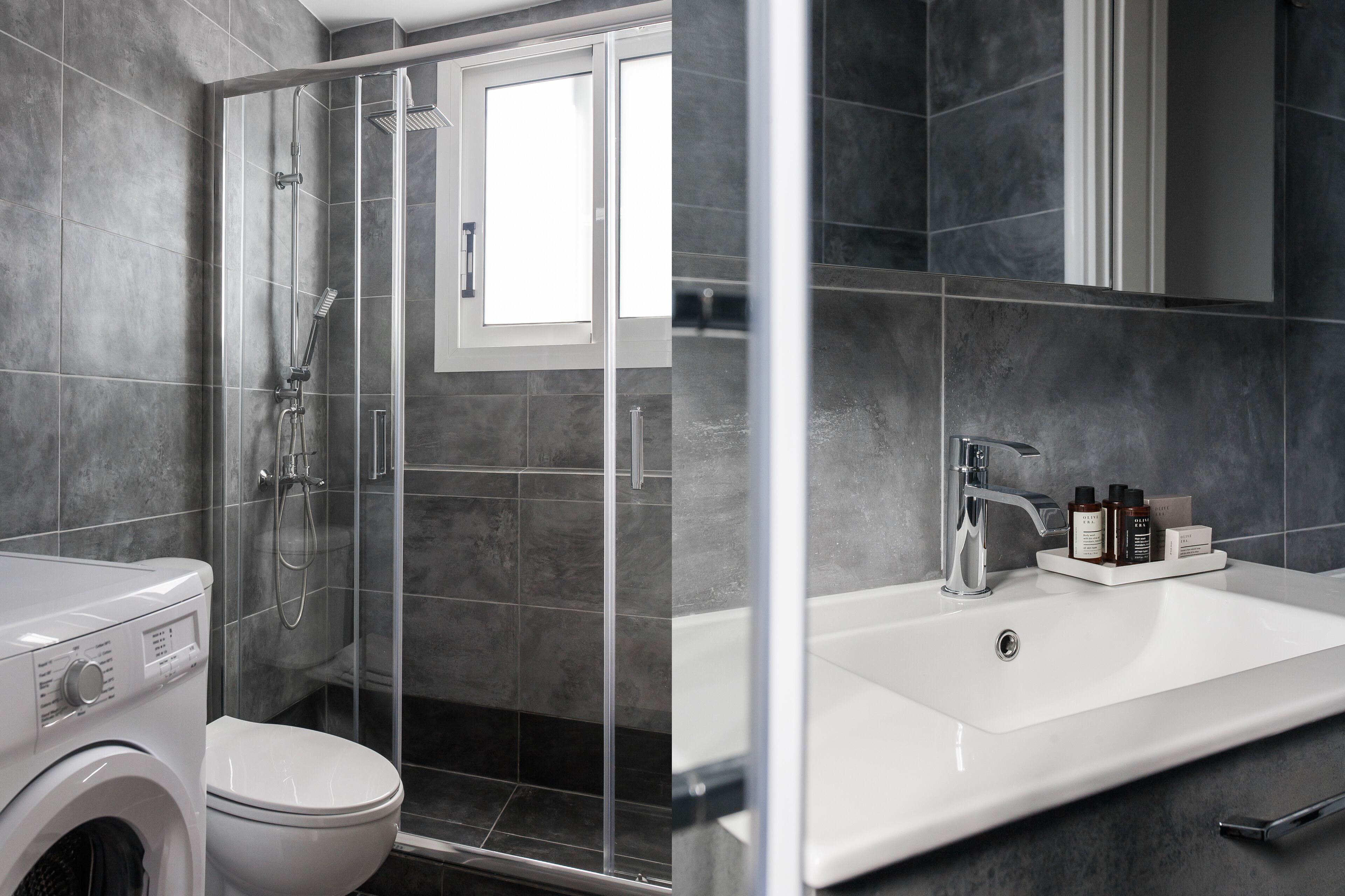 A modern bathroom with a glass-enclosed shower, a white sink with toiletries, and a washing machine.
