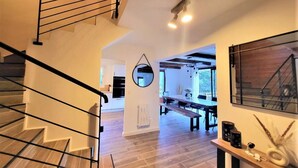 Un interior modern amb una escala, una zona de menjador i un gran mirall.