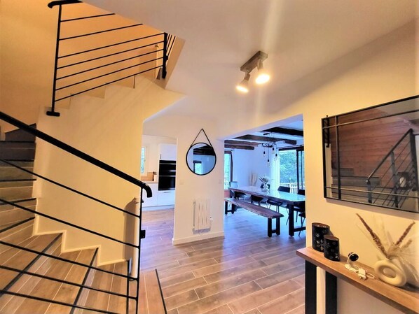 Ein modernes Interieur mit Treppe, Essbereich und einem großen Spiegel.