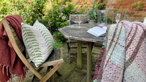 A rustic outdoor seating area with a wooden table, a bench, and a potted plant.